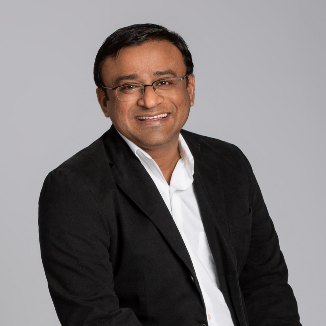 Dr. Pradeep Adatrow, board-certified periodontal and dental implant surgeon, and prosthodontist, smiling professionally in a white coat.