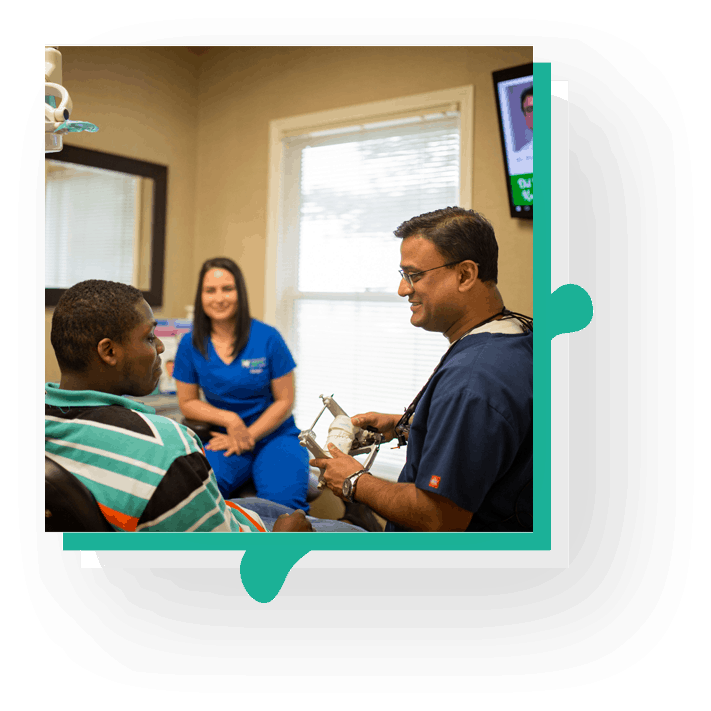 Dr. Pradeep Adatrow smiling with a patient in a dental clinic, showcasing expertise in dental implants, smile transformations, and professional dental care.